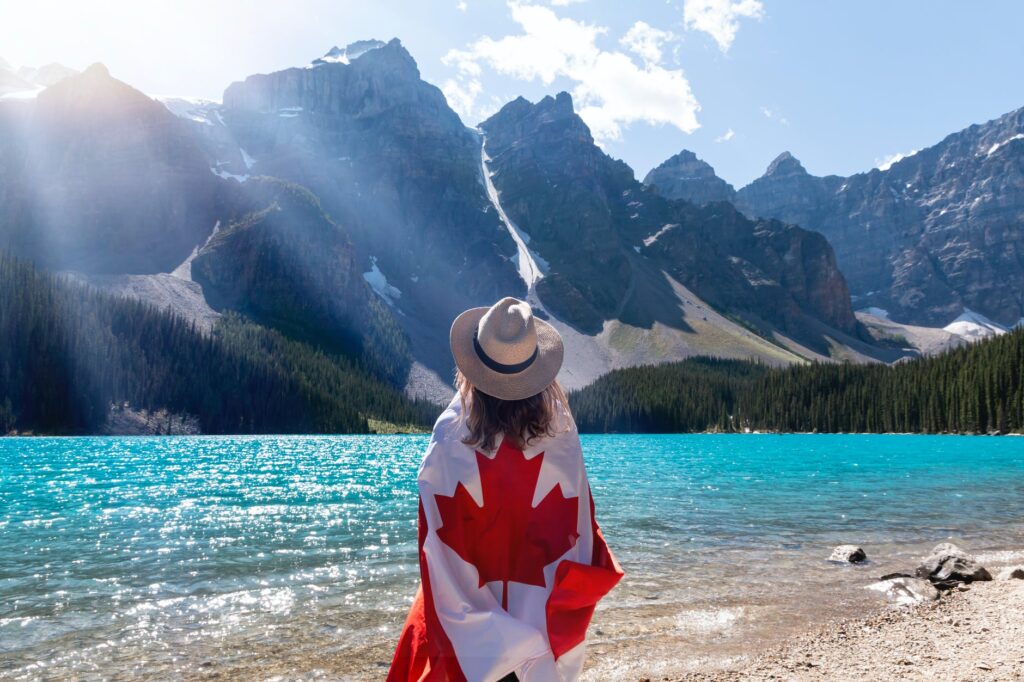 person with a canadian flag around her standing near lake